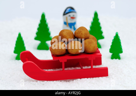 Marzipan-Kartoffeln auf einer roten Schlitten, Schnee-Szene Stockfoto