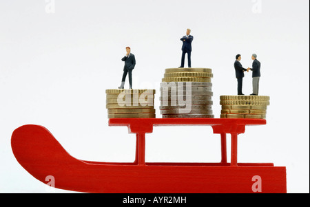 Geschäftsleuten stehen auf Stapel von Euro-Münzen auf einem roten Schlitten Stockfoto