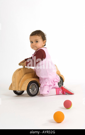 Kleine Mädchen spielen mit hölzernen Wagen und Kugeln Stockfoto