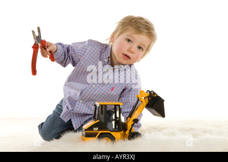 Zwei-jährigen Kleinkind Zange halten und spielen mit einem Spielzeug Bagger Stockfoto