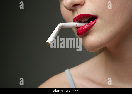 Junge Frau mit einer gebrochenen Zigarette im Mund (Teil), Nahaufnahme Stockfoto