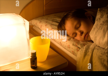 Medizin auf Nachttisch neben ein Kind im Bett schlafen Stockfoto