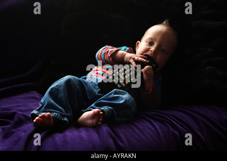 Sechs Monate altes Baby Boy mit der Fernbedienung auf der couch Stockfoto