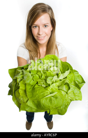 Lächelnde junge Frau mit langen Haaren bieten einen großen Kopf grüner Salat Stockfoto