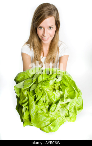 Lächelnde junge Frau mit langen Haaren bieten einen großen Kopf grüner Salat Stockfoto