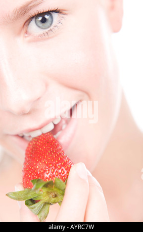 Junge Frau, die eine Erdbeere essen Stockfoto