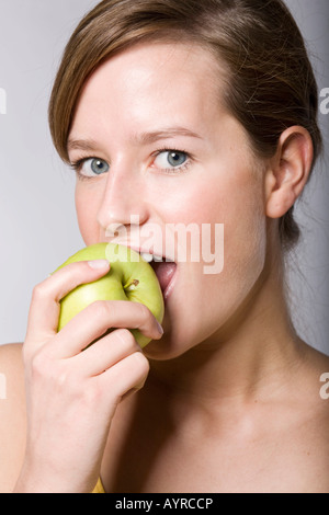 Junge Frau in einem grünen Apfel beißen Stockfoto