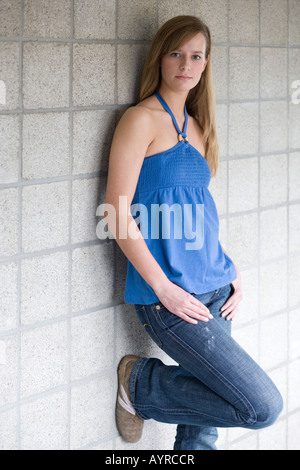 Junge Frau ein Zement Ziegelwand gelehnt Stockfoto