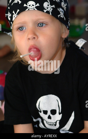 Mädchen mit Piratensymbole von Schädel und gekreuzte Schwerter auf ihr Hemd saugen ihr lolly Stockfoto