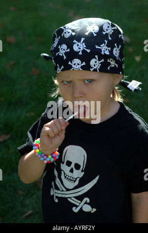 Mädchen mit Piratensymbole von Schädel und gekreuzte Schwerter auf ihr Hemd, ihr Lolly lecken Stockfoto