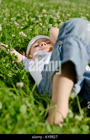 Mädchen, die Verlegung auf einem Kleeblatt Wiese im Sommer träumen Stockfoto