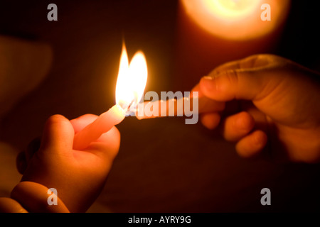 Hände des Kindes eine Kerze anzünden Stockfoto
