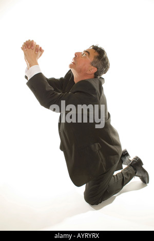 Kniende Geschäftsmann beten um Gnade Stockfoto