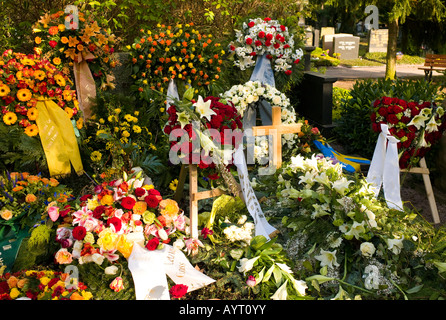 Frischen Grab geschmückt mit unzähligen Blüten auf einem Friedhof in Deutschland Stockfoto