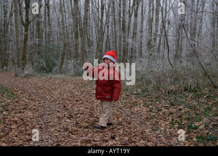 kleiner Junge mit Weihnachtsmütze allein im tiefen Wald Punkte fragend aus frame Stockfoto