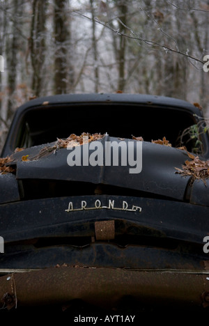 nach oben auf der Vorderseite des alten verlassenen schwarzen Oldtimer liegen in einem winterlichen Wald Stockfoto