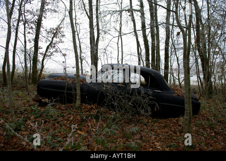 Seite auf Sicht der alten verlassenen schwarzen Oldtimer liegen in einem winterlichen Wald vergessene Stockfoto