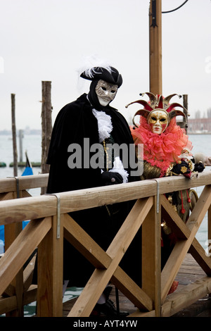 Menschen tragen schwarz/weiß und rot Kostüme und Masken stehen auf einem Dock, Carnevale di Venezia, Karneval in Venedig, Italien Stockfoto