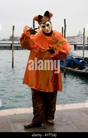 Golden Harlekin (Hofnarr) Kostüm und Maske vor Gondeln, Carnevale di Venezia, Karneval in Venedig, Italien Stockfoto