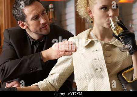 Frau trinkt ein Glas Champagner, Mann, sie zu berühren Stockfoto