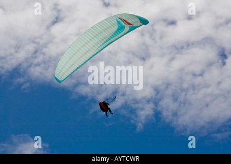 Hängegleiter und Pilot gegen einen hellen blauen und bewölkten Himmel in Norfolk, England Stockfoto