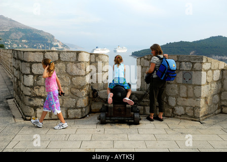 Mutter und 2 Kinder, einer Sitzung auf Kanone, Stadt Wand Brüstung für Kreuzfahrtschiffe in Ferne durchsehen. Dubrovnik, Kroatien Stockfoto