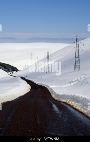 Die A939 Lecht Straßenlauf, von Cockbridge nach Tomintoul, Schottland, mit Schnee auf den umliegenden Hügeln in der Wintersonne Stockfoto