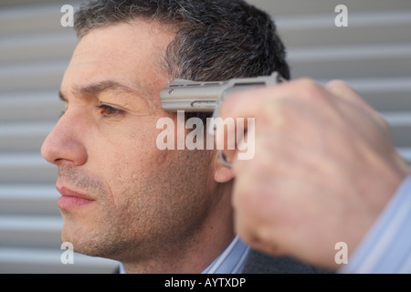 Geschäftsmann mit einer Pistole an Kopf Stockfoto