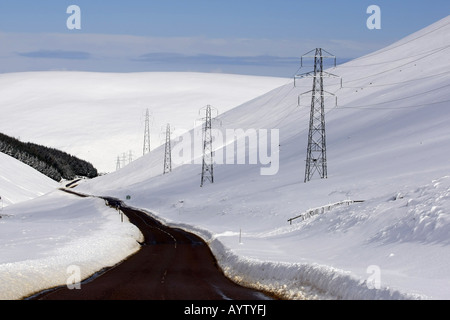 Die A939 Lecht Straßenlauf, von Cockbridge nach Tomintoul, Schottland, mit Schnee auf den umliegenden Hügeln in der Wintersonne Stockfoto