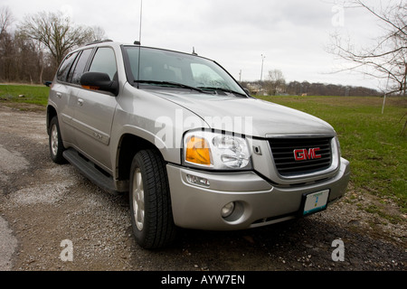 Ein GMC Envoy sitzt auf einem Schotterweg neben einem leeren Fußballplatz. Stockfoto