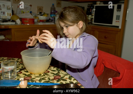 Olivia brechen Eiern in Schüssel während des Kochens Sitzung mit Oma, die Herstellung von Kuchen in Küche Cotswolds UK Stockfoto