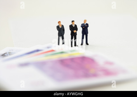 Drei Unternehmer Figurinen und Banknoten Stockfoto
