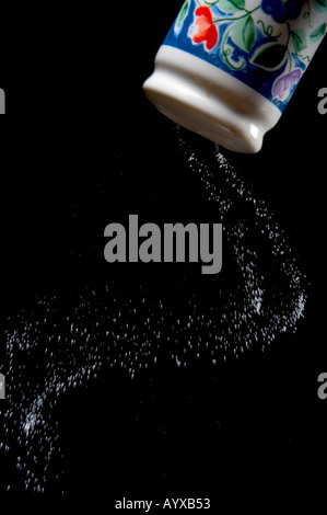 Salz aus Salzstreuer in Aktion erschossen auf schwarzem Hintergrund Stockfoto