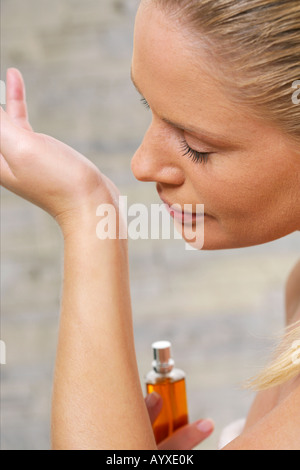 Junge Frau, die auf Seite Parfüm riechen Stockfoto