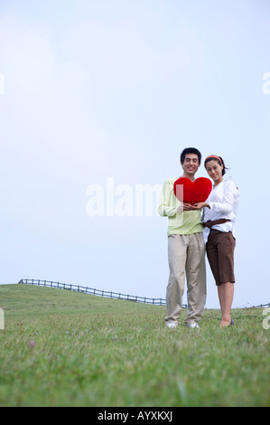 ein paar stehen mit der holding Kleinigkeit Artikel in Herzform Stockfoto