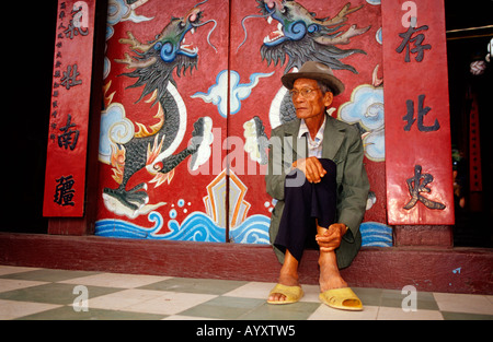 Hoi an Vietnam. Älterer Mann sitzt vor dem Haupteingang des Quan Cong Budhist chinesischen Tempel. Stockfoto