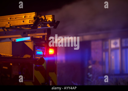 Notdienste Feuerwehr Lkw mit Rot und Blau blinkende Lichter und Leiter außerhalb einer inländischen Haus Feuer in Großbritannien geparkt Stockfoto