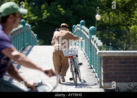 Ein älterer Radfahrer schiebt ihr Fahrrad über eine Fußgängerbrücke in Berlin Deutschland Stockfoto