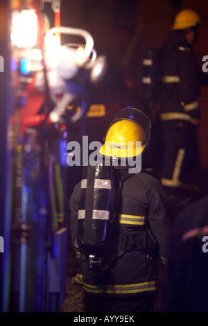 Feuerwehrmann Atemschutzgerät tragen wartet im hinteren Teil ein Feuerwehrauto zart am Unfallort einen Hausbrand im Vereinigten Königreich Stockfoto