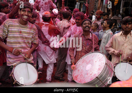 Gruppe von Indianern, die während des Holi Festivals in Paharganj auf der Straße von Neu-Delhi tanzen, Trommeln spielen und mit rosa Puder feiern. Stockfoto