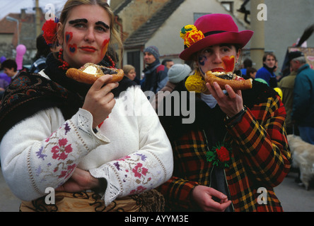 Zwei Frauen in Trachten gekleidet sind traditionelle Kuchen essen, während der traditionelle Karneval in Mokropsy, Tschechische Republik Stockfoto
