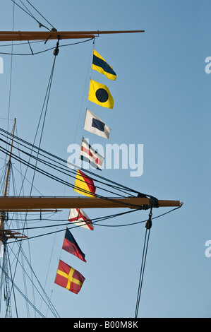 Signalflaggen vom Mast eines Segelschiffes, gegen den blauen Himmel fliegen Stockfoto