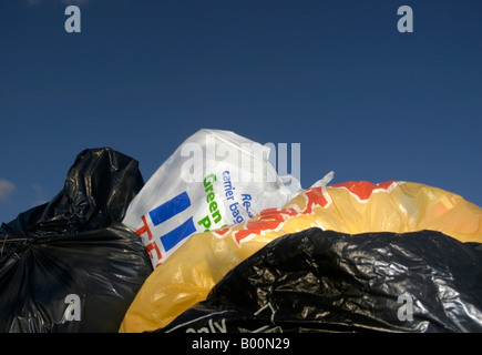 Blaue kommerzielle Wheelie bin überfüllt mit Plastiktüten Müll sitzen in einem ländlichen Layby mit einem klaren blauen Himmel 3/3 Stockfoto