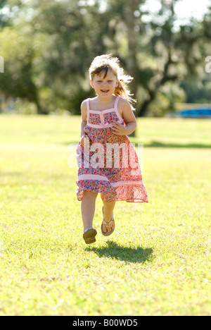 Glück läuft im Park an einem sonnigen Tag, vier Jahre alten Mädchen in volllaufen, beide Füße über dem Boden. Stockfoto