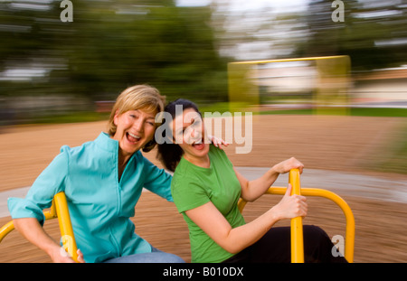 Mutter und Tochter oder gute Freunde, die Spaß beim Spielplatz Spinnen wie Unschärfe auf Mary gehen um lachen Stockfoto