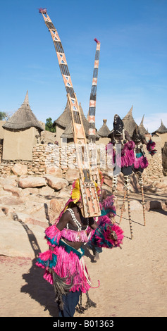 Mali, Dogonland, Tereli. Maskierte Tänzer tragen die fünfzehn Fuß hohe Sirige Maske und Stelzenläufer Tänzer treten bei Tereli. Stockfoto