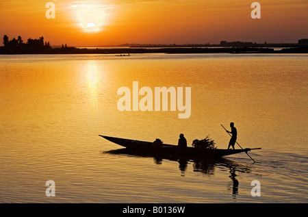 Mali, Mopti. Bei Sonnenuntergang Fähren ein Fährmann in einer Piroge Passagiere über den Fluss Niger, Mopti. Stockfoto