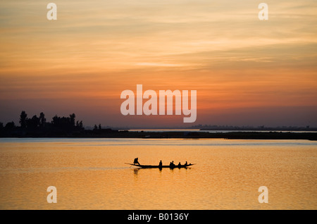 Mali, Mopti. Bei Sonnenuntergang Fähren ein Fährmann in einer Piroge Passagiere über den Fluss Niger, Mopti. Stockfoto