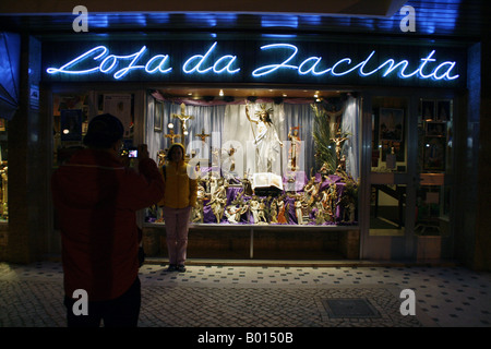 2 Touristen posieren vor einem Geschäft mit katholischen Souvenirs in Fatima, Portugal Stockfoto