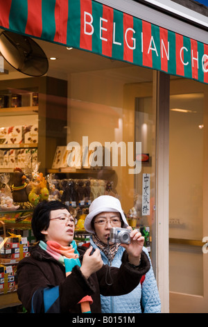 Japanische Frau Touristen betrachten einer Digitalkamera vor Schokoladengeschäft in Brüssel, Belgien. Stockfoto